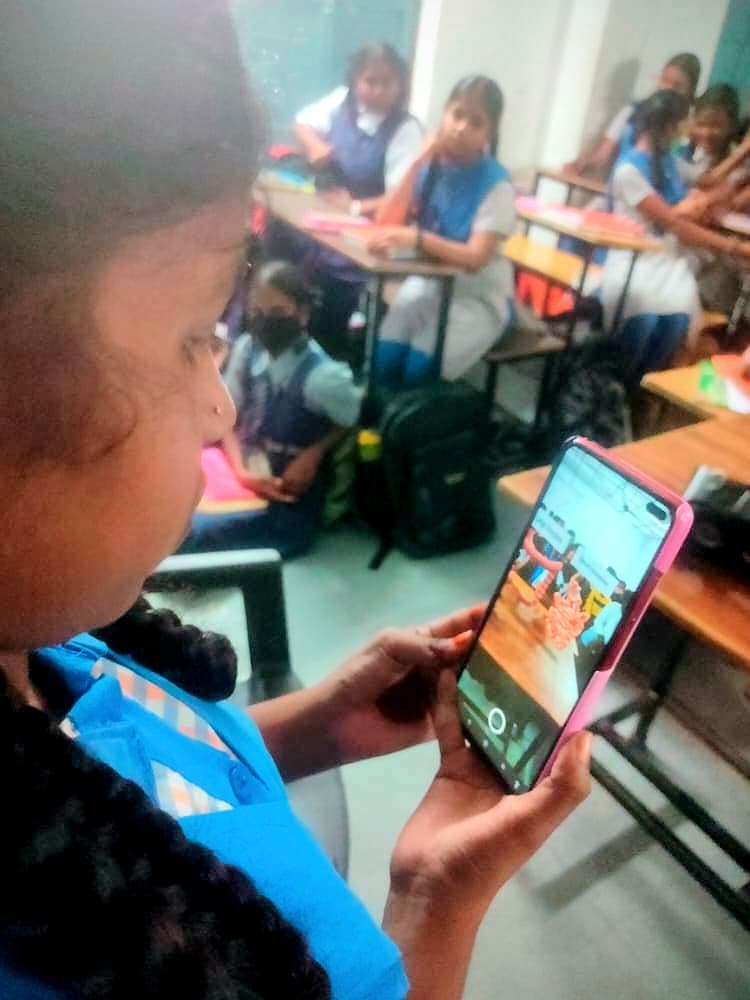 A student scanning an AR sticker with a phone in a classroom